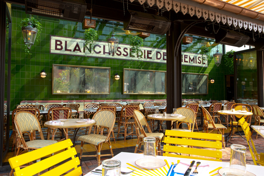 Sunny sidewalk seating outside Le Diplomate in Washington, DC with colorful chairs and vintage Parisian decor.